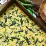 Frittata di asparagi appena sfornata, ricca di verdure e formaggio, pronta per essere gustata con pane integrale.