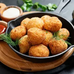 Croccanti polpette di zucca dorate servite in una padella di ghisa, con salse e erbe aromatiche.