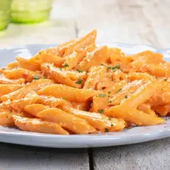 Penne cremose con salsa rosa, un piatto di pasta veloce e sfiziosa, guarnito con prezzemolo e parmigiano.