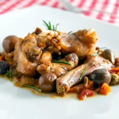 Coniglio alla cacciatora ricetta della nonna: succulenti pezzi di coniglio con olive, pomodorini e rosmarino, un classico sapore di casa.