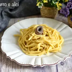 Un piatto di pasta burro e alici, semplice e gustoso, con un'alice arrotolata in cima.