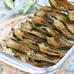 Friggitelli al forno, tagliati a metà e conditi con pangrattato e formaggio, pronti per essere gustati.