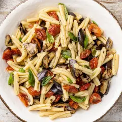 Pasta fredda con melanzane grigliate, pomodorini secchi e basilico fresco, un piatto estivo colorato e saporito.