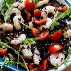 Riso Venere freddo con gamberetti, pomodorini e rucola, un piatto fresco e colorato.