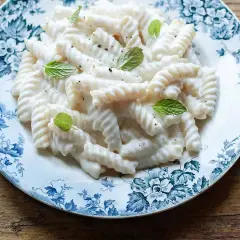 Fusilli cremosi con salsa alla ricotta, guarniti con menta fresca. Un'idea semplice per le tue ricette di pasta con ricotta.
