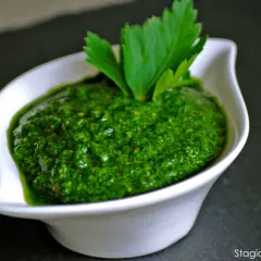 Una ciotola bianca contiene una vibrante ricetta salsa verde leggera, guarnita con prezzemolo fresco.