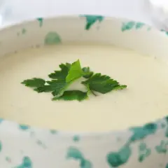 Una ciotola decorata con una vellutata crema di parmigiano, guarnita con prezzemolo fresco.