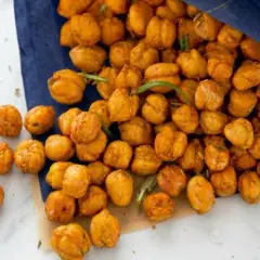 Ceci croccanti al forno, dorati e speziati, versati da un sacchetto blu. Perfetti per uno snack salutare.
