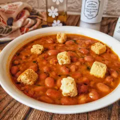 Una ciotola di zuppa di fagioli fumante, guarnita con crostini croccanti, pronta per essere gustata.
