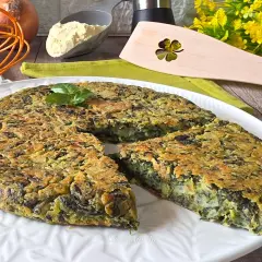 Frittata di spinaci dorata e soffice, guarnita con basilico fresco, pronta per essere gustata.