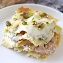 Un invitante primo piatto della domenica: lasagna cremosa con ragù rosa e pistacchi croccanti.