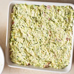 Sformato di zucchine pronto per essere infornato, con zucchine grattugiate e un cremoso impasto.