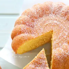 Una soffice torta di zucca, cosparsa di zucchero a velo, con una fetta tagliata. Perfetta per l'autunno.