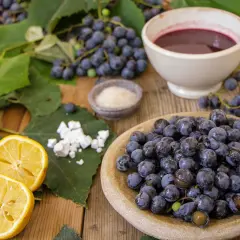 Uva fragola fresca, limone, zucchero e una ciotola di succo scuro, ingredienti per una deliziosa marmellata.