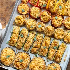 Verdure gratinate al forno: zucchine, melanzane, pomodori e peperoni ripieni di pangrattato e erbe aromatiche, cotti su una teglia.