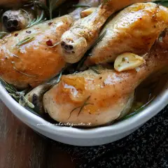 Succulente sovracosce di pollo al forno, dorate e profumate con aglio e rosmarino, servite in una ciotola bianca.