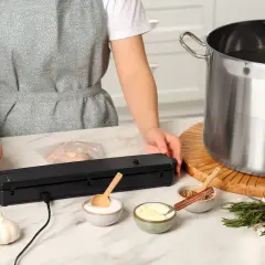 Persona prepara il pollo sottovuoto per la cottura a bassa temperatura, con ingredienti e attrezzatura a portata di mano.