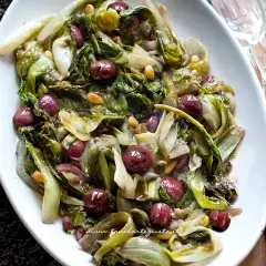 Scarola in padella con olive e pinoli, un contorno saporito e colorato, pronto per essere gustato.