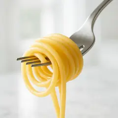 Un gomitolo di pasta di semola avvolto su una forchetta, pronto per essere gustato.