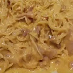 Un piatto cremoso di pasta alla carbonara, con spaghetti avvolti in una salsa dorata e pezzetti di guanciale.