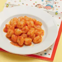 Un piatto di chicche di patate condite con un sugo rosso, servite su un tovagliolo colorato.