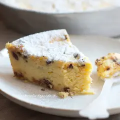 Una fetta di torta ricotta veloce, soffice e cosparsa di zucchero a velo, con gocce di cioccolato. Un assaggio delizioso.