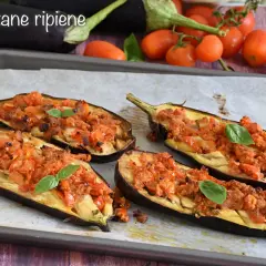 Melanzane ripiene senza carne, un piatto saporito e colorato, con pomodorini e basilico fresco.