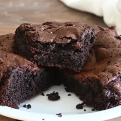 Torta al cioccolato, soffice e umida, tagliata a fette su un piatto bianco. La crosta è leggermente screpolata, rivelando l'interno scuro e invitante.