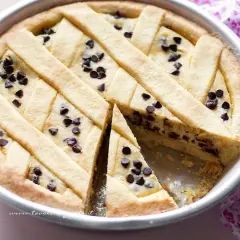 Una deliziosa crostata di ricotta con gocce di cioccolato, con una fetta tagliata per mostrare il ripieno cremoso.