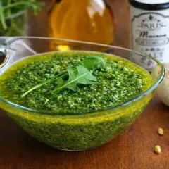 Pesto di rucola Bimby pronto in ciotola, con rucola fresca, pinoli e aglio. Un condimento saporito e facile da preparare.