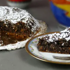 Torta Caprese, ricetta originale napoletana, con una fetta servita su un piatto decorato.