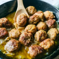 Polpette in bianco succulente in padella con cipolle caramellate, pronte per essere gustate.