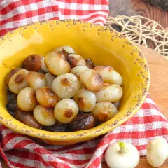 Cipolline in agrodolce caramellate in una ciotola gialla, servite su un tagliere di legno con tovagliolo a quadri rossi.