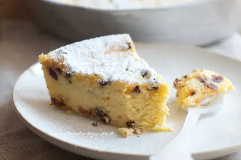 Una fetta di torta ricotta veloce, soffice e cosparsa di zucchero a velo, con gocce di cioccolato. Un assaggio delizioso.