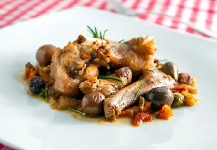 Coniglio alla cacciatora ricetta della nonna: succulenti pezzi di coniglio con olive, pomodorini e rosmarino, un classico sapore di casa.