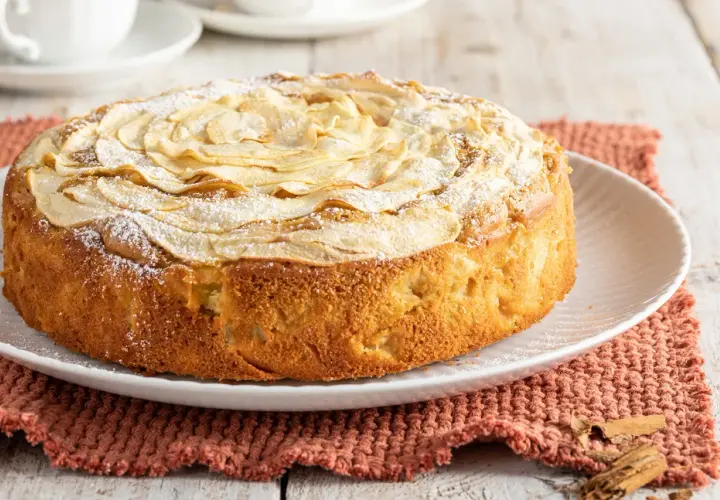 Una deliziosa torta di mele senza burro, decorata con fettine di mela e zucchero a velo, pronta per essere gustata.