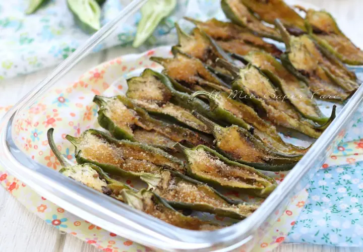 Friggitelli al forno, tagliati a metà e conditi con pangrattato e formaggio, pronti per essere gustati.