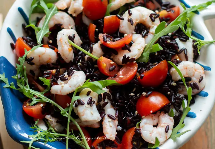 Riso Venere freddo con gamberetti, pomodorini e rucola, un piatto fresco e colorato.