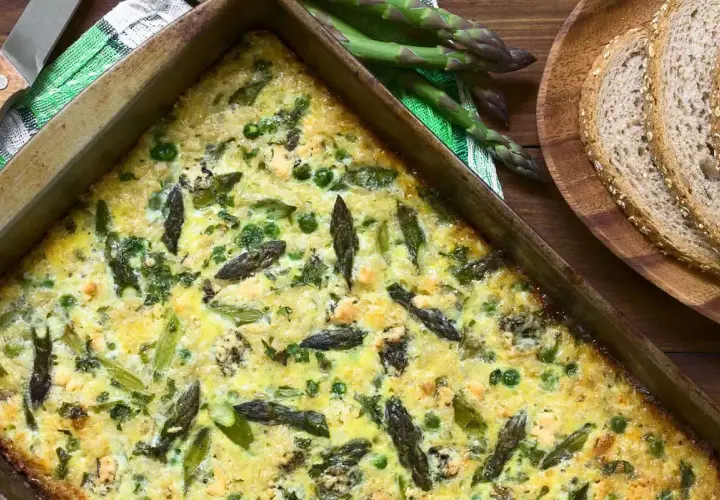 Frittata di asparagi appena sfornata, ricca di verdure e formaggio, pronta per essere gustata con pane integrale.