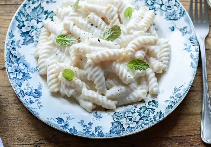 Fusilli cremosi con salsa alla ricotta, guarniti con menta fresca. Un'idea semplice per le tue ricette di pasta con ricotta.