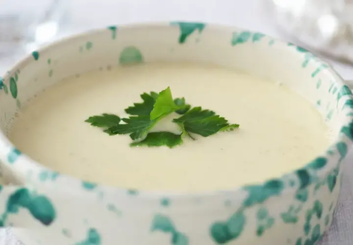Una ciotola decorata con una vellutata crema di parmigiano, guarnita con prezzemolo fresco.