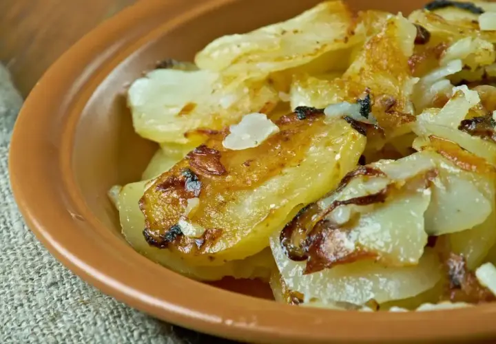 Patate alla lionese dorate e croccanti, servite in una ciotola di terracotta. Un classico saporito.