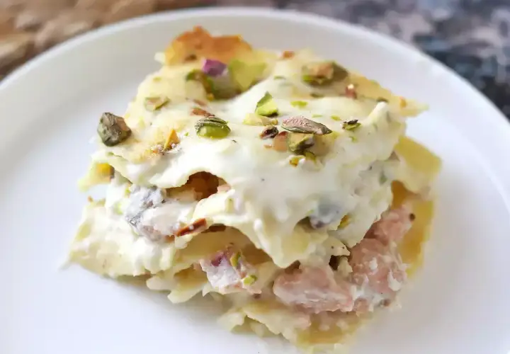 Un invitante primo piatto della domenica: lasagna cremosa con ragù rosa e pistacchi croccanti.