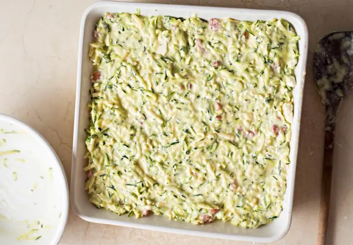 Sformato di zucchine pronto per essere infornato, con zucchine grattugiate e un cremoso impasto.