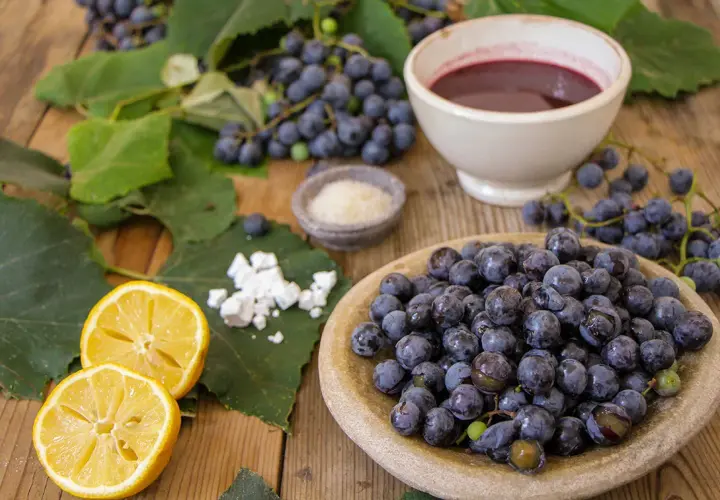 Uva fragola fresca, limone, zucchero e una ciotola di succo scuro, ingredienti per una deliziosa marmellata.