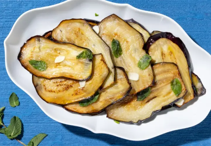 Fette di melanzane grigliate, condite con aglio e menta, un contorno di verdure saporito e colorato.