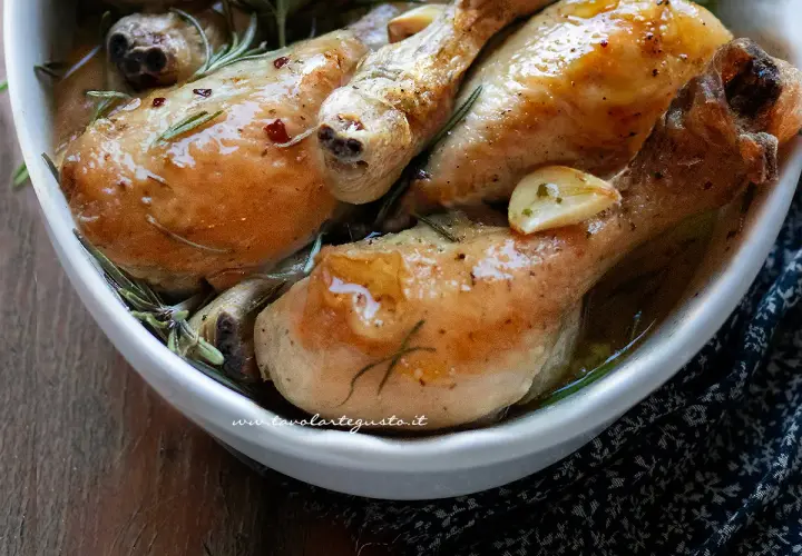 Succulente sovracosce di pollo al forno, dorate e profumate con aglio e rosmarino, servite in una ciotola bianca.
