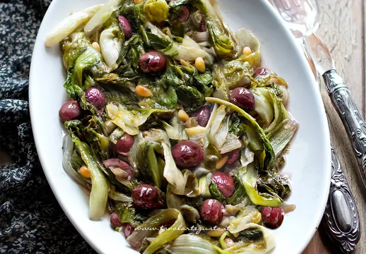 Scarola in padella con olive e pinoli, un contorno saporito e colorato, pronto per essere gustato.