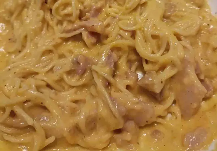 Un piatto cremoso di pasta alla carbonara, con spaghetti avvolti in una salsa dorata e pezzetti di guanciale.