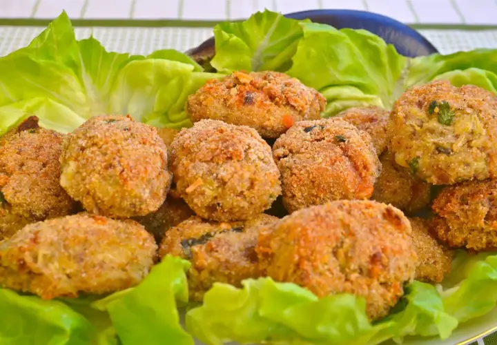 Polpette di melanzane fritte dorate e croccanti, servite su un letto di lattuga fresca.
